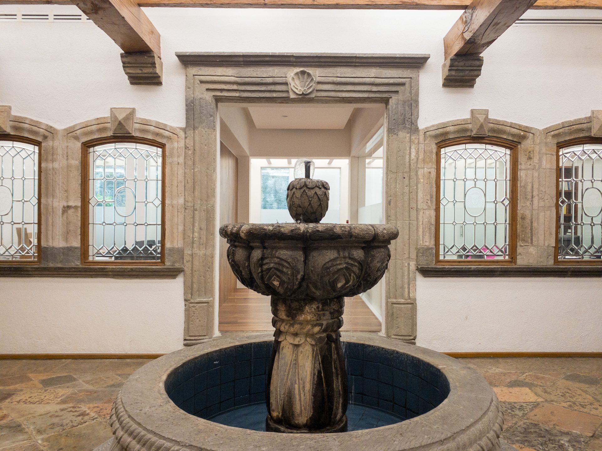 Fuente de cantera del despacho enmarcada por vitrales emplomados