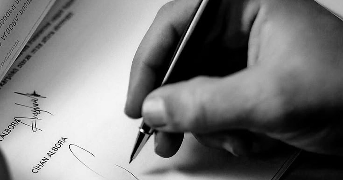 Primer plano de una mano firmando un documento con pluma